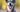 Happy gray dog with tongue out smiling in a sunny outdoor setting, closeup portrait capturing joyful expression and bright eyes.