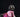 Adorable small dog wearing a pink plaid sweater and rainbow tutu poses on a dark background for a stylish pet photo shoot.
