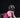 Adorable small dog wearing a pink plaid sweater and rainbow tutu poses on a dark background for a stylish pet photo shoot.